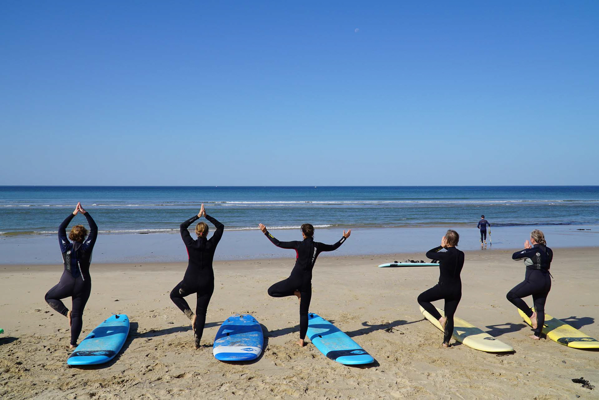 5 Surfende am Strand beim Yoga